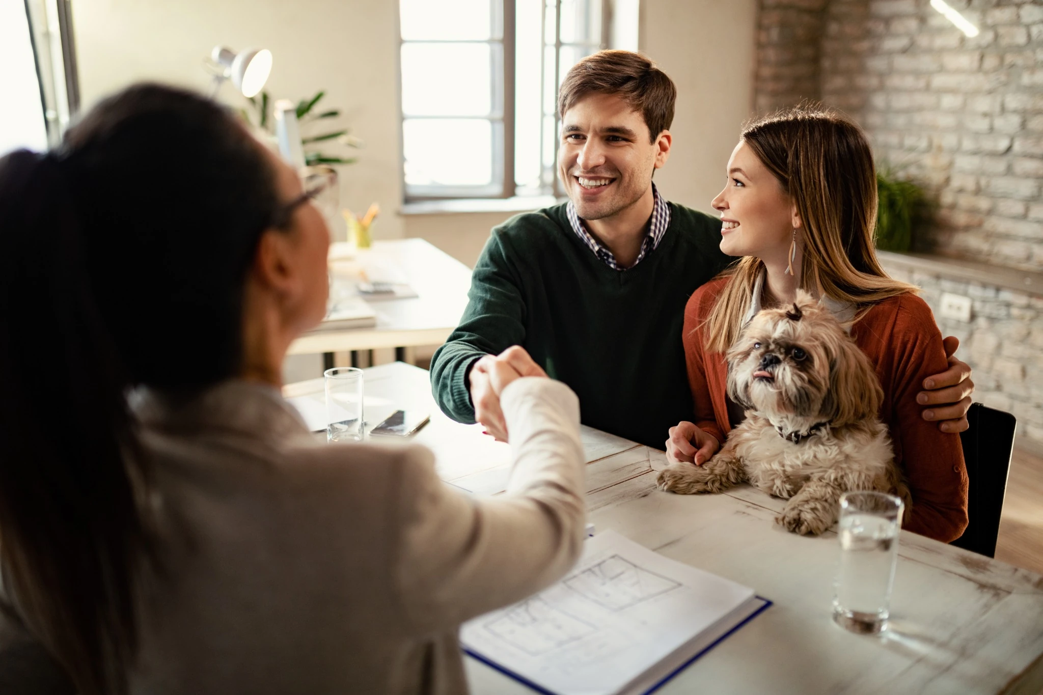 Casal com cão a cumprimentar uma consultora numa reunião